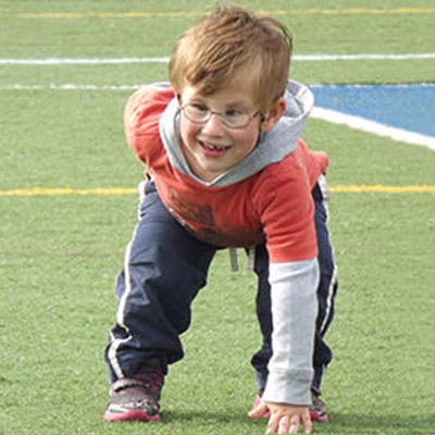Young boy with LS kneeling on football field