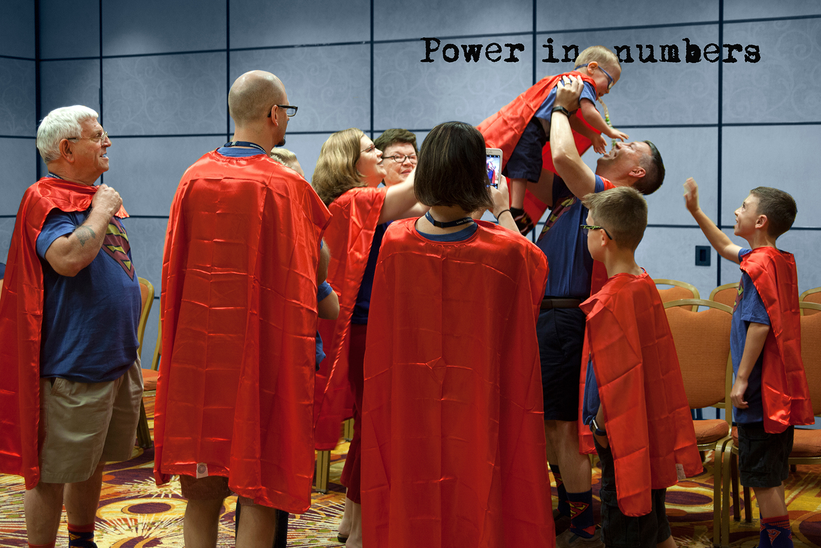Family wearing Super hero capes lifting up boy in the air